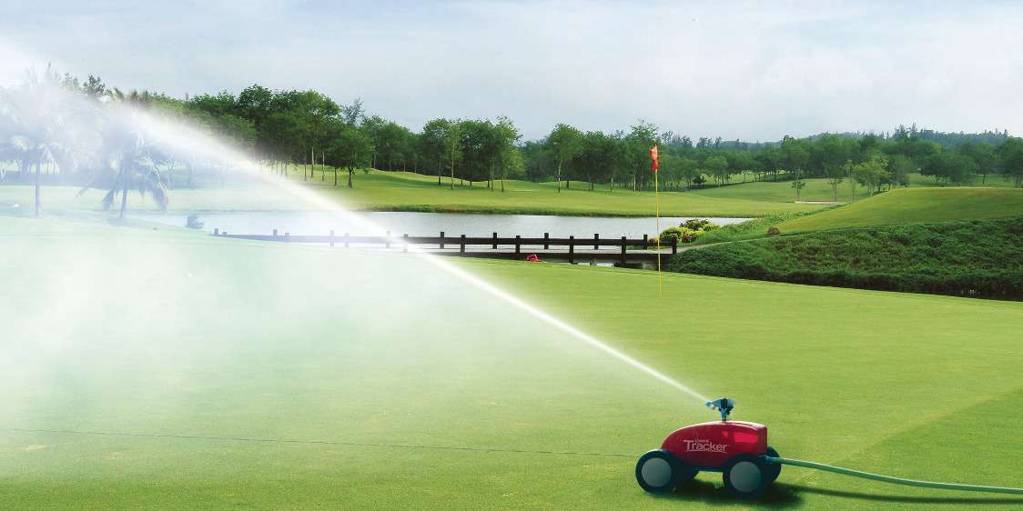Water sprinkler irrigating golf course lawn.