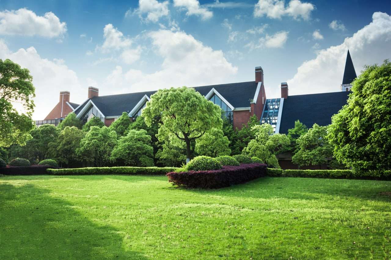 Lush garden fronting traditional brick building with blue sky.